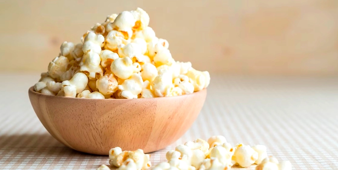 Wooden bowl filled with fresh, fluffy white popcorn.